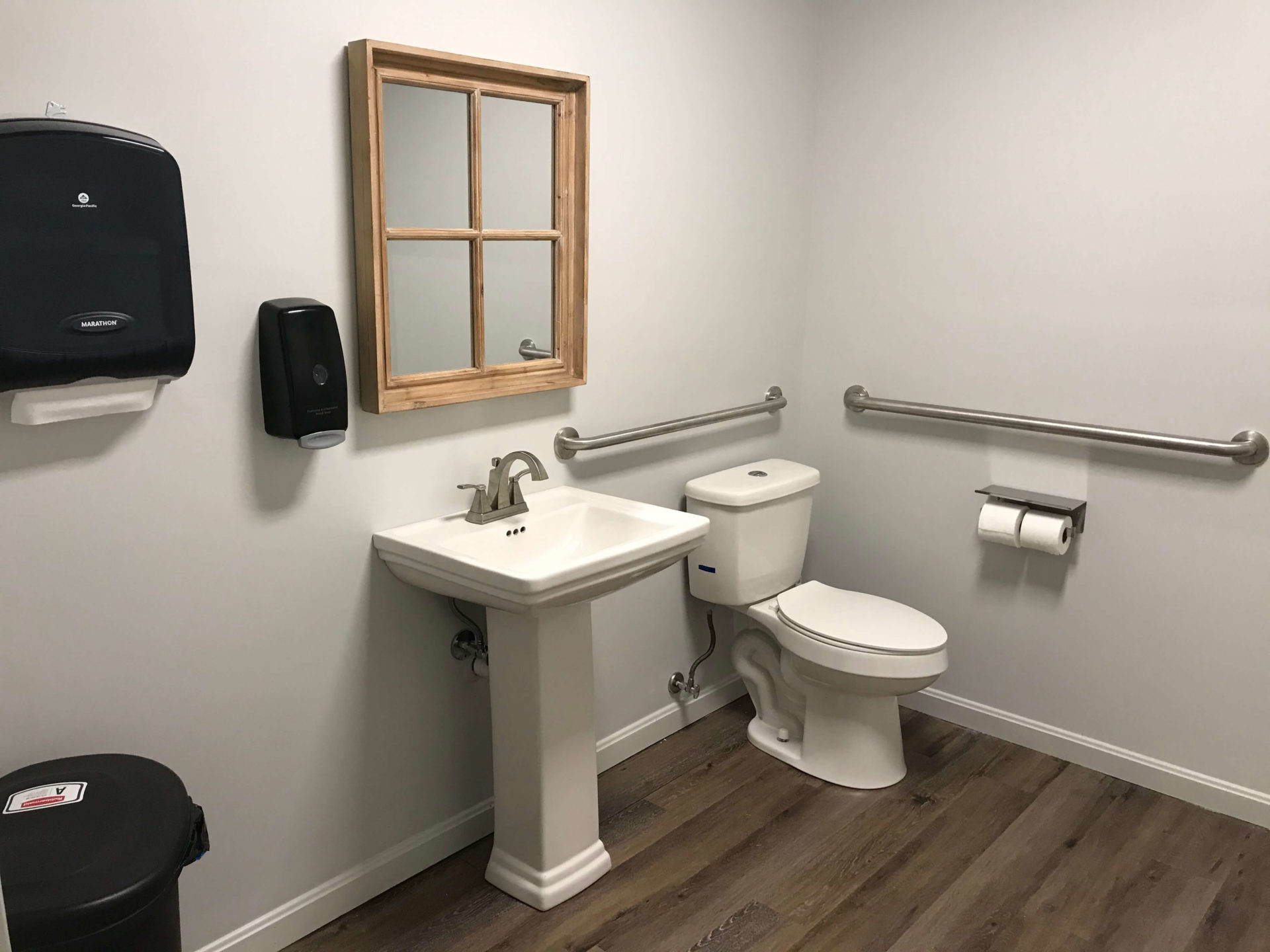 bathroom with ADA accessible toilet and sink with mirror, soap dispenser, and automatic towels
